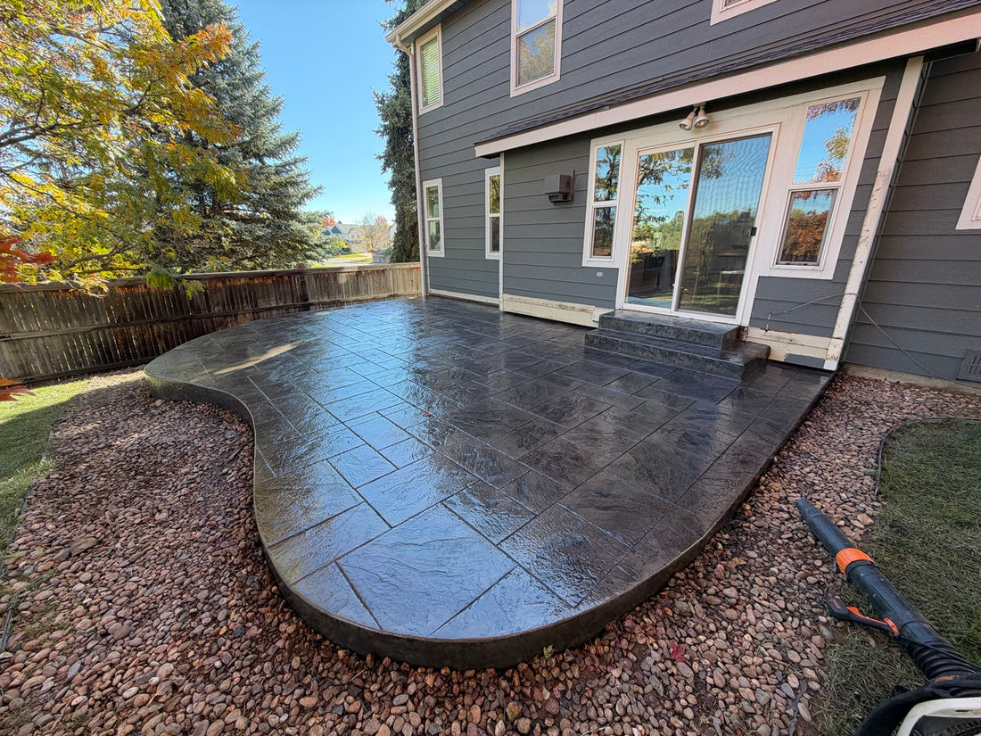 Ashlar Cut Slate stamped concrete patio with charcoal-gray coloring, curved borders, and decorative rock landscaping at a Ken Caryl home.
