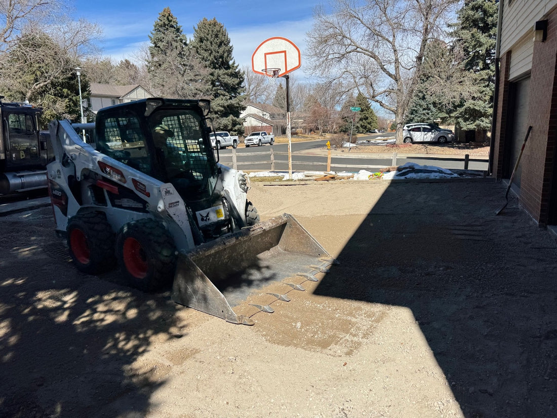 Skid steer excavating residential driveway area before new concrete installation in Denver Colorado