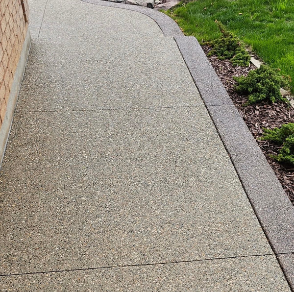 Exposed aggregate concrete walkway with decorative border and visible stone texture